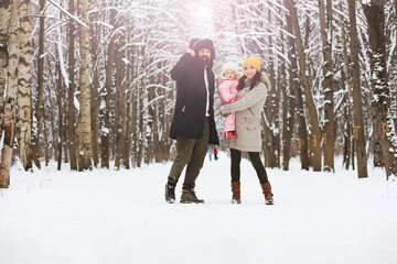 Happy family playing and laughing in winter outdoors in the snow. City park winter day.