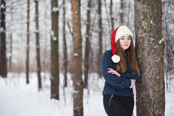 A young girl in a winter park on a walk. Christmas holidays in the winter forest. The girl enjoys winter in the park.