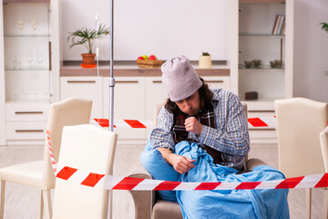 Young sick man suffering at home in pandemic concept