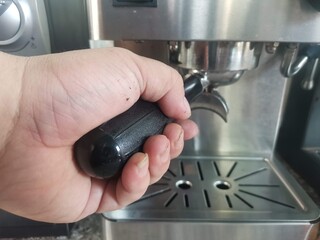 Hand holding the Bottomless and put it into the machine to prepare the coffee.