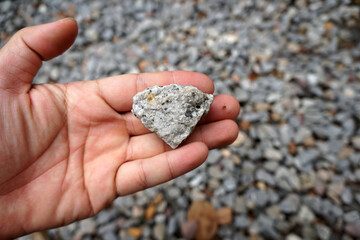 a piece of pegmatite granite rock in a hand. Igneous Rock Specimen.