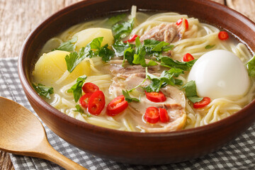 South American Caldo de Gallina chicken noodle soup with boiled egg and herbs close-up in a plate on the table. horizontal