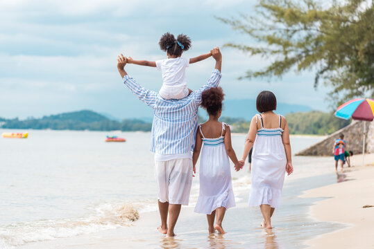 Happy African American family with African American father / asian mother and mixed race kids walking on the beach, thaliand