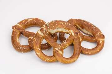 Knusprig braune Brezeln (Laugengebäck) liegen gefächert neben- und aufeinander auf einem neutralen weißen Hintergrund