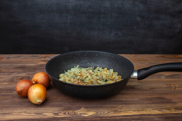 Frying pan with fried onions, three onions side by side. Chalk board in the background