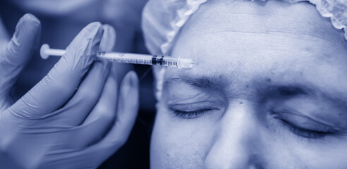 Middle age woman getting skin care injection, blue tinting, close up. Platelet Rich Plasma for...