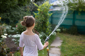 teenage girl playing water fight and splashing water from garden hose