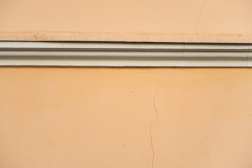 Plastered wall of an old building with a cornice and a thin crack, background