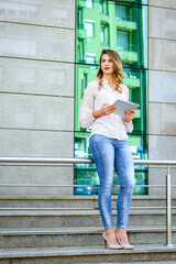 Businesswoman working on digital tablet outdoor over building background.