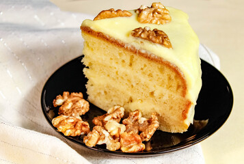 A piece of homemade cake with cream, decorated with walnuts.
