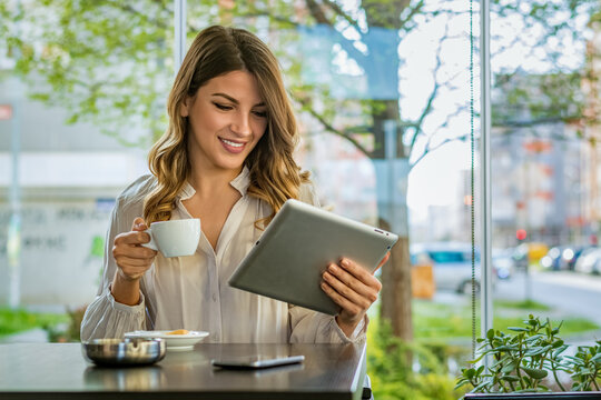 Young woman Typing on tablet, chatting, maintains a blog. Freelancer work in cafe modern coworking. Successful people, businessman in comfortable cafe .