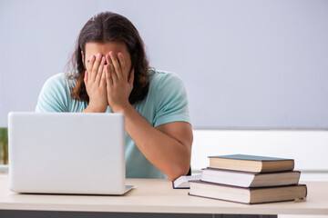 Young male student preparing for exams in tele-education concept