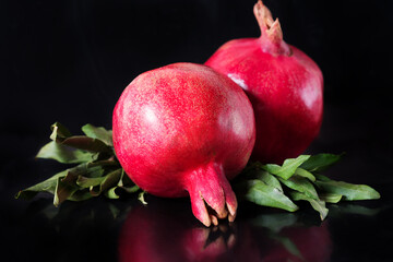 whole pomegranate fruit with leaves on a black background
