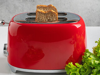 Stylish red toster for bread. Stylish Breakfast. Modern appliances. Toast with salad. English breakfast. Slices of bread in the toaster. - obrazy, fototapety, plakaty