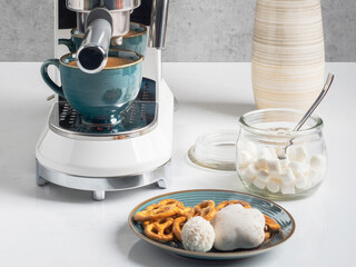 Coffee is freshly made with a coffee machine. With marshmallows. Cookies and sweets for coffee. White coffee machine. Modern mug. Turquoise ceramic mug.