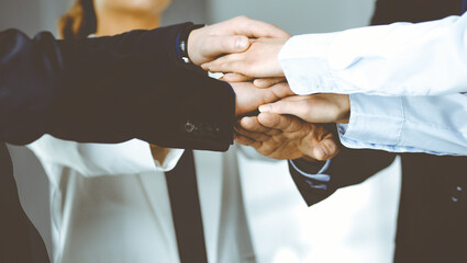 Group of unknown businesspeople are joining hands in a modern office. Unknown businessmen are making circle with their hands. Concept of trust and support in a business - 397557683