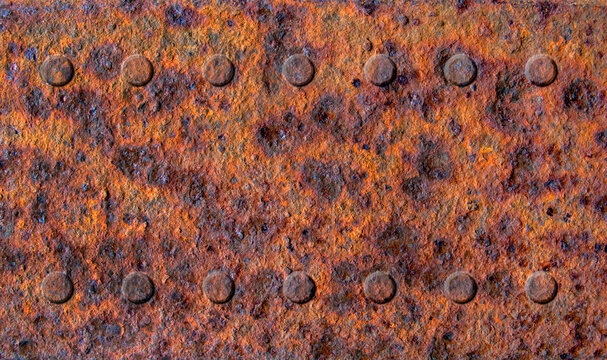 Old rusty stained metal sheet with two rows of rivets close up, metal texture or background 