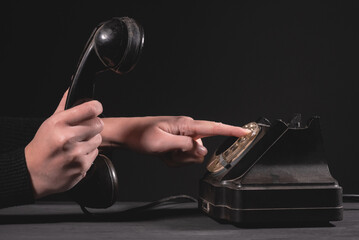Woman is dialing the number on the old rotary phone close up.