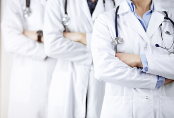 Group of modern doctors standing as a team with arms crossed in sunny hospital and ready to help patients. Medical help, insurance in health care