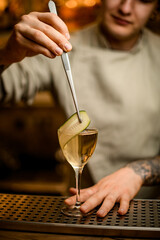 Fototapeta na wymiar bartender decorates cocktail glass with cucumber slice using tweezers