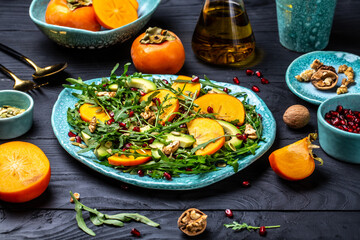 food prepare in process vegetarian salad by chef hand in home kitchen, vegan persimmon salad with arugula, avocado, pumpkin seeds, walnuts, pomegranate, Vegan food. Flat lay