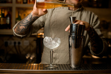 metal glasses of shaker and wine glass with ice stands on the bar.