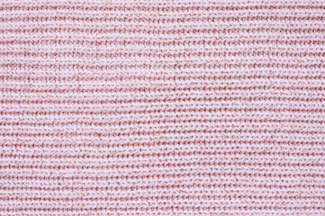 Pink knitted fabric texture. Knitted background with horizontal direction. Focusing in the center of the frame