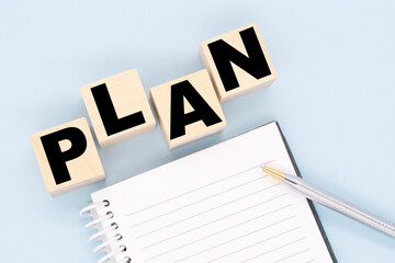 2021 plan, finance plan abstract design concept, wood blocks and a diary with a pen on blue background, top view, flat lay, copy space