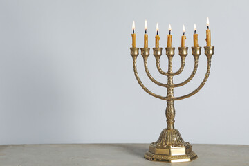 Golden menorah with burning candles on table against light grey background, space for text - obrazy, fototapety, plakaty