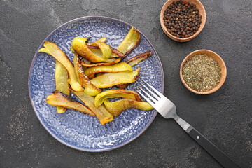 Plate with roasted peppers and spices on dark table