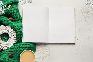 Blank book with Christmas decor and cup of coffee on white background