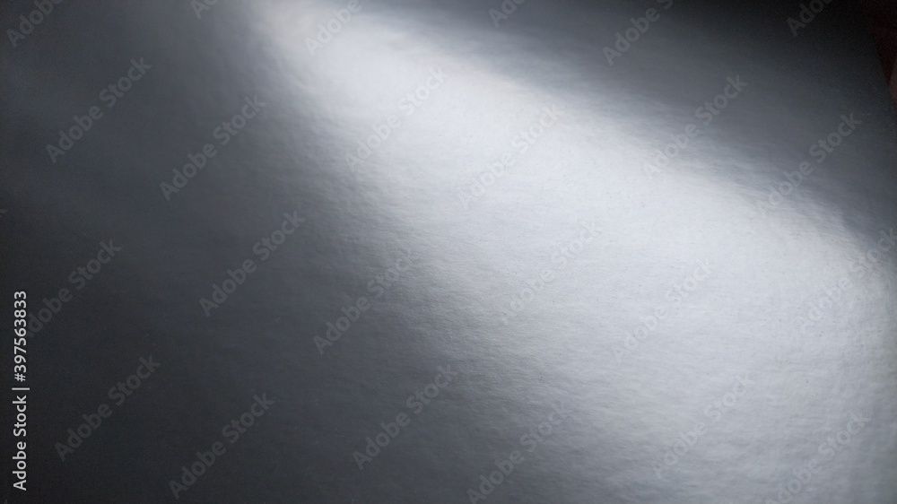 Poster long flare of light on shiny gray paper. a light spot on a monochrome surface that reflects light. a