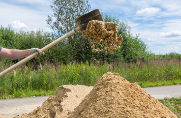 a shovel worker throws quarry sand into a large pile © ILIA