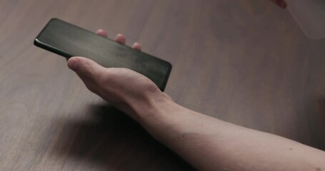 Slow motion man hand sanitizing smartphone with spray over walnut wood table - Powered by Adobe