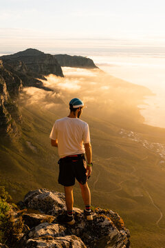 A trail runner enjoying the view of the sunset over the ocean from the top of Table Mountain in Cape Town