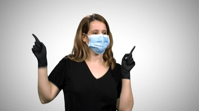 Woman with surgical mask and gloves dancing and celebrating, extremely happy, over white background.
