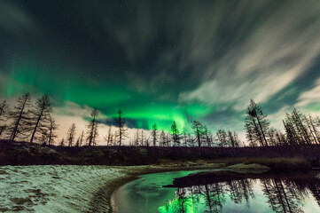 Northern lights Shine through clouds with reflection in water