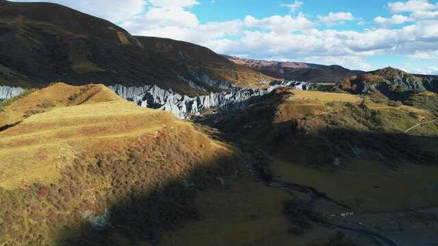 Aerial scenery of Moshi Park,Tagong Grassland.White clouds floating in azure sky.Russet mantle clad covering hills.Grey stone forests standing among hills.