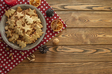 Plate of delicious homemade holiday shaped cookies on a red tablecloth on a wooden table. Concept of creating a cozy atmosphere and festive mood. Top view and copy space