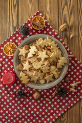 A plate of delicious homemade holiday shaped cookies on a red tablecloth on a wooden table. Concept of creating a cozy atmosphere and festive mood. Top view