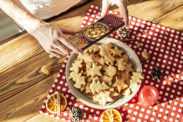 A woman is taking photos a plate with delicious homemade figure holiday cookies on her phone camera