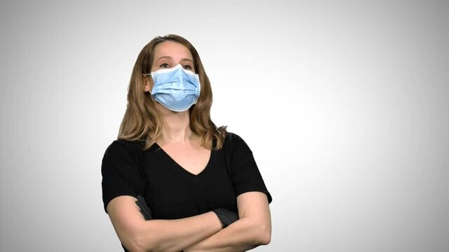 Woman with surgical mask and gloves standing with crossed arms and looking to the camera dramatically, signs "heart", over white background.