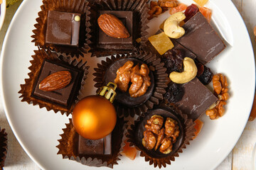 sweet food background for christmas or holiday decoration - chocolate candies, tangerines, nuts and dried fruits on white wood