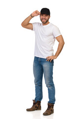 Fototapeta premium Smiling Young Man In Jeans, White T-shirt Is Standing And Posing In Black Cap