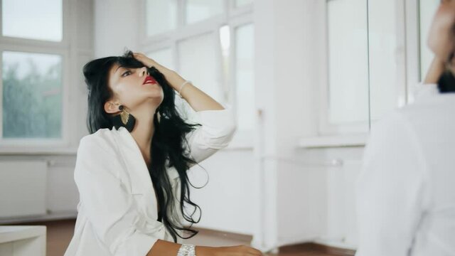 Sensualny taniec, czarnowłosej pięknej młodej tancerki w białym pomieszczeniu w zwolnionym tempie
