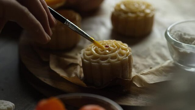 Chef hand making Mooncake a Chinese traditional pastry for Mid-Autumn festival. set on rustic wooden table.