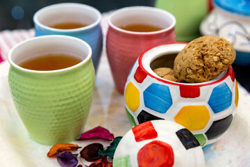 Colorful pot of cookies, and tea cups on a serving tray. Selective focus on colorful ceramic pot. Food and Beverages Stock Image.