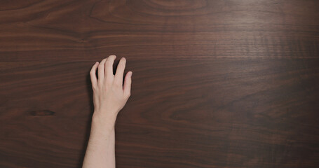 Top view man hand finger tap on black walnut table with copy space