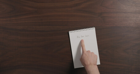 Obraz premium Top view man show notepad with new year goals on walnut wood table