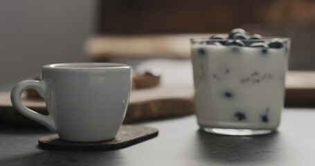 espresso cup next to granola with blueberries in glass with copy space